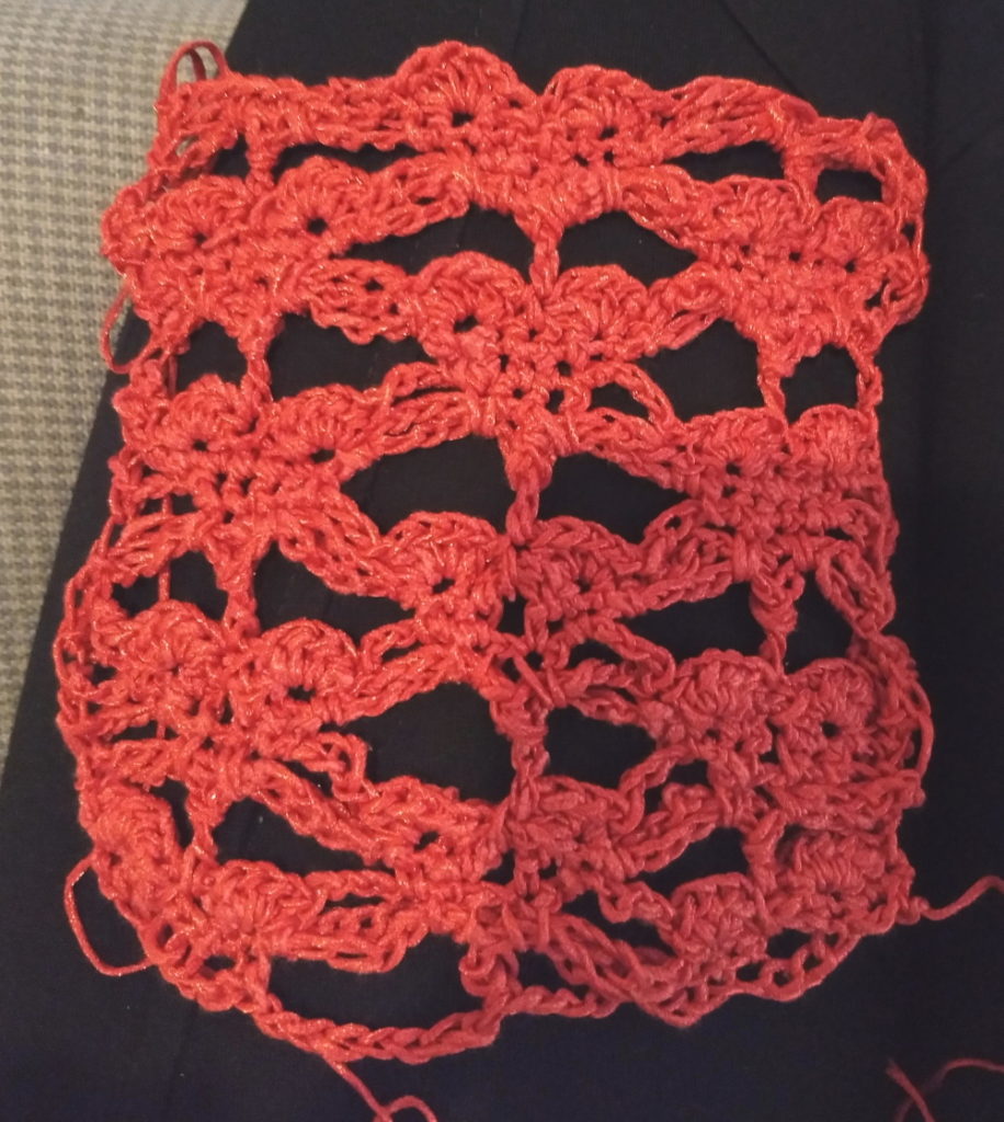 A sample of crocheted lace showing messy unidentifiable shapes on the bottom row with heart-looking shapes on the top.