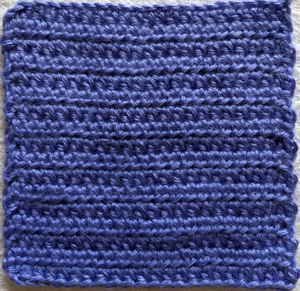A purple crocheted square using half double crochet stitches