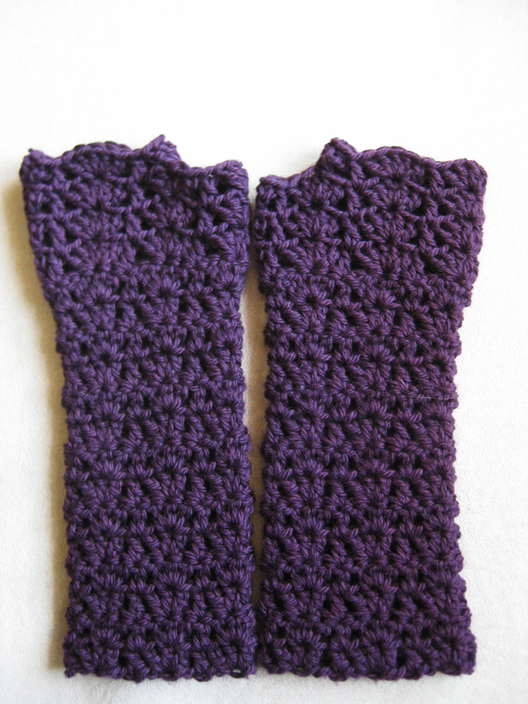 Kait crochet pattern purple fingerless gloves with lacy shell stitches on a white background