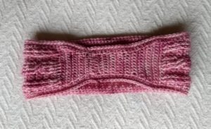 The back of a pinc crocheted headband showing a narrowing at the back portion