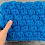 woman holding chunky blue crocheted neckwarmer