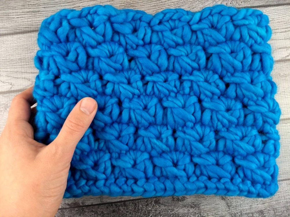 woman holding chunky blue crocheted neckwarmer