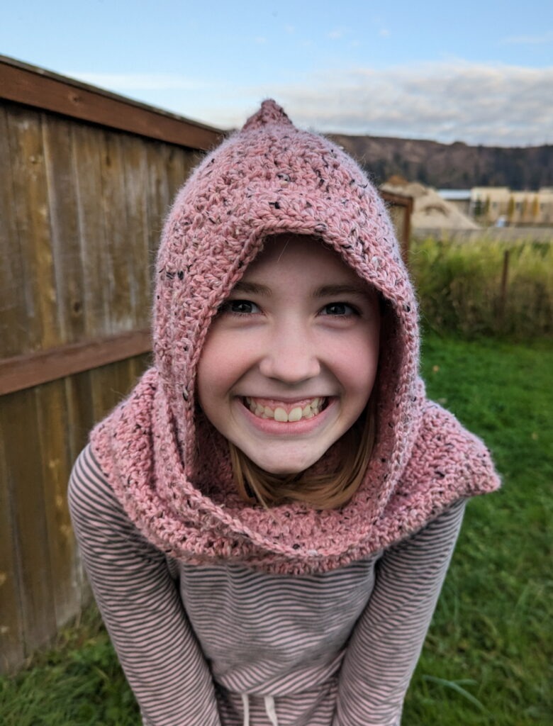 Blonde Girl Wearing Pink Hooded Crochet Scarf made with WeCrochet City Tweed Yarn